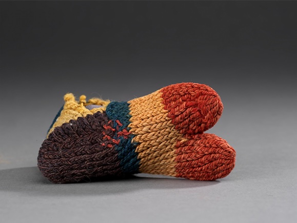 Knitted, multi-colored baby booties in brown, red, and orange.