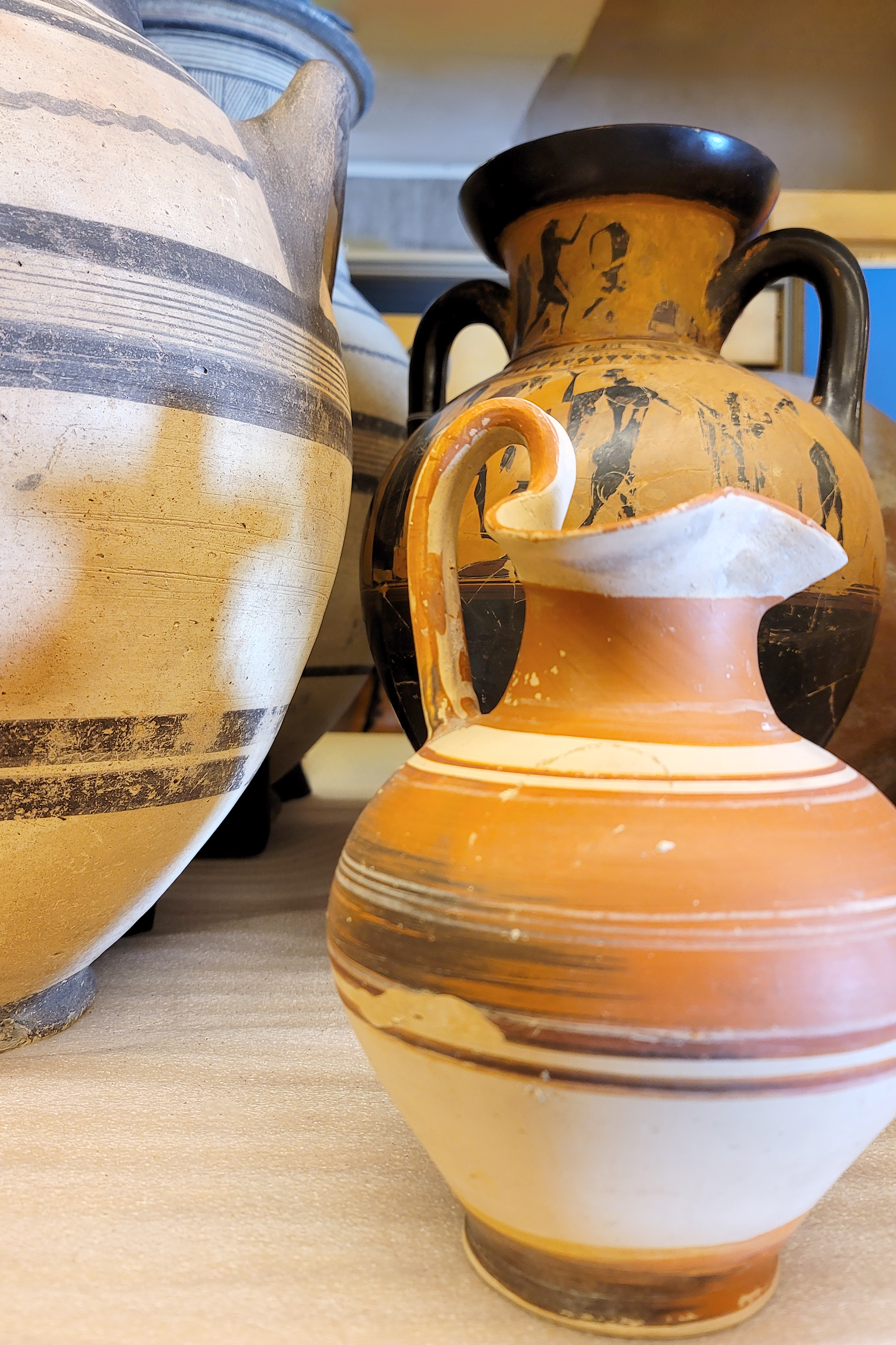 A ceramic vase with two handles featuring brown, orange, white, and black bands and geometric designs.