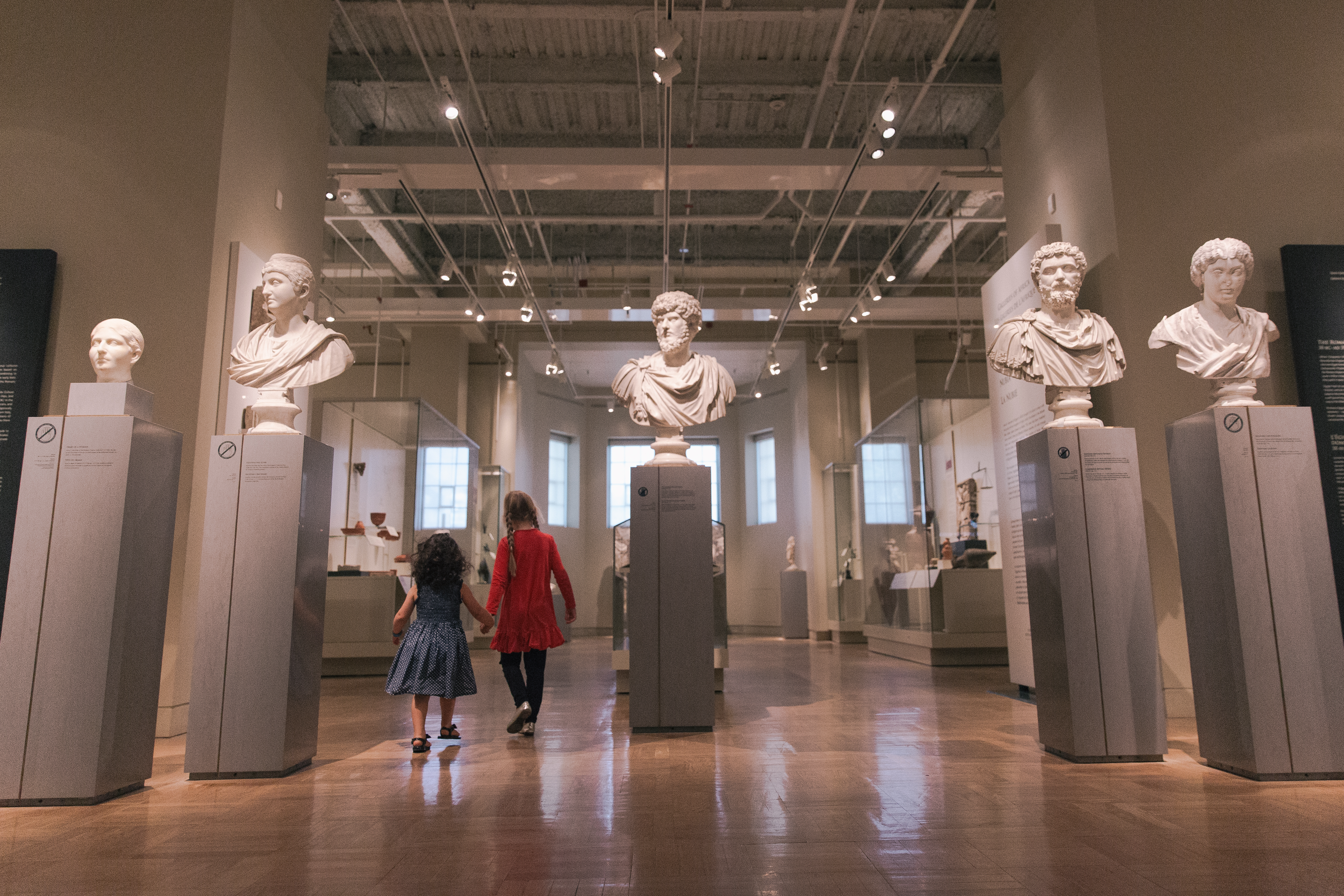 two people walking through the Roman portrait display in the Gallery of Rome.