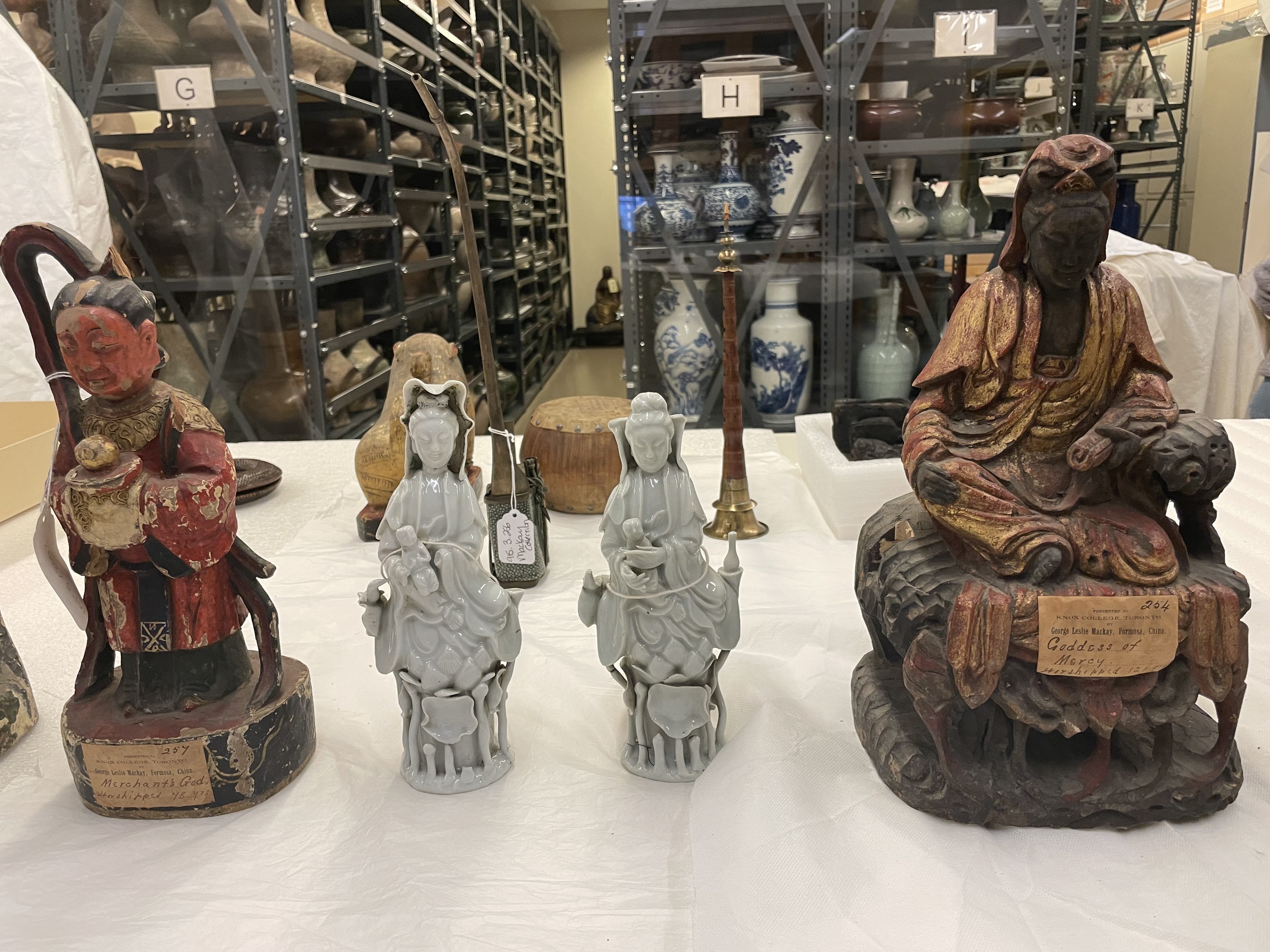 Two seated figurines on either side of four small standing white statues arranged in a row.