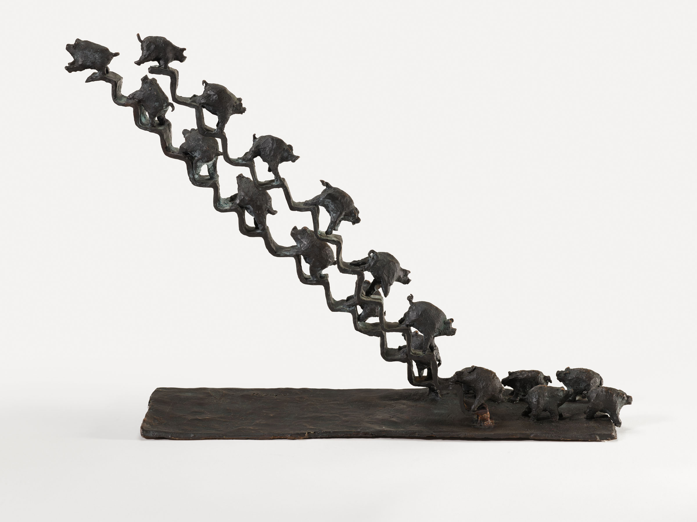 Bronze sculpture of a diagonal row of small frogs leaping upward from a flat base with three frogs on the ground.