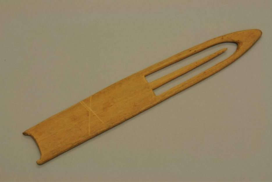 Pièce de bois sculptée avec une pointe et une aiguille pointue à l'intérieur d'un espace découpé à la pointe.