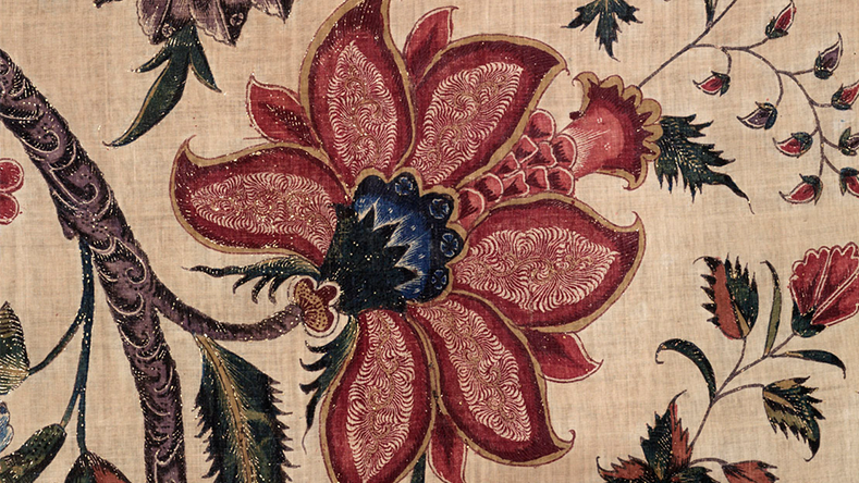 Red and cream floral pattern on a textile with intricate detailing and a blue center.