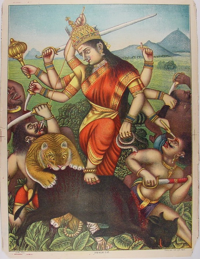 A multi-armed goddess wearing a crown and red sari stands on a tiger while holding various weapons, surrounded by weapons and a mountain background.
