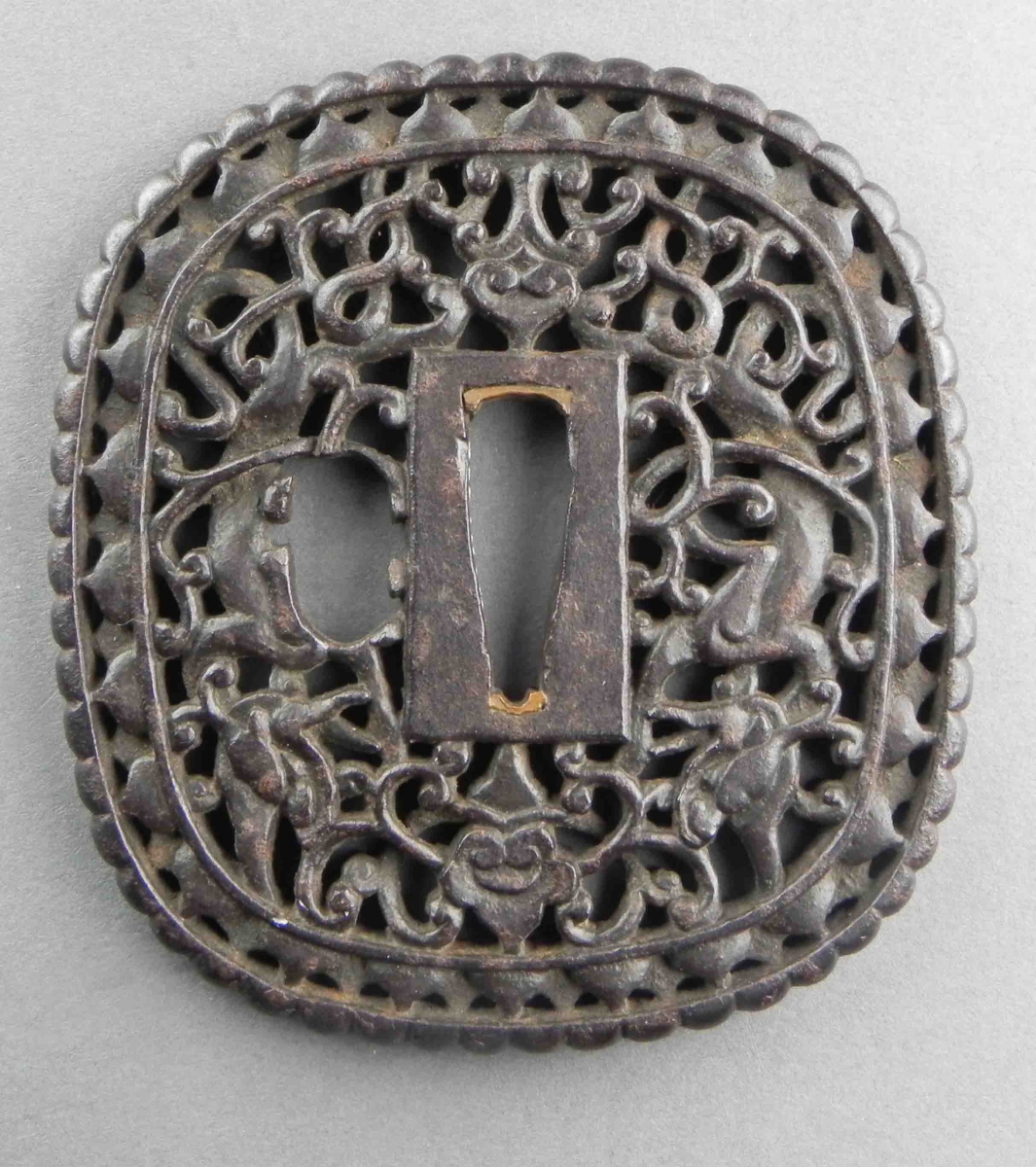 Tsuba carrée en métal avec des motifs floraux et de vigne ajourés entourant une ouverture centrale rectangulaire.