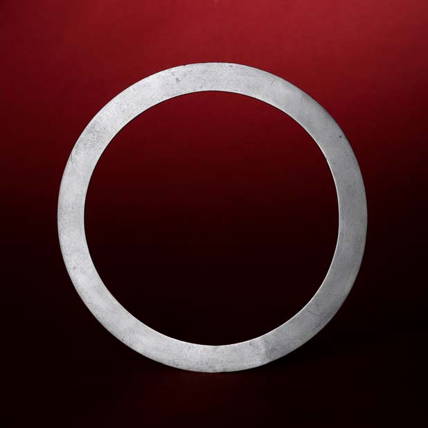 A simple, textured silver ring on a dark red background.