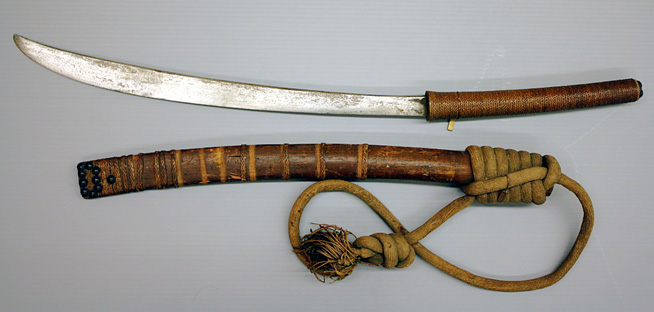 Curved sword with a wrapped wooden handle and sheath, bound with cord and featuring a looped corded strap.