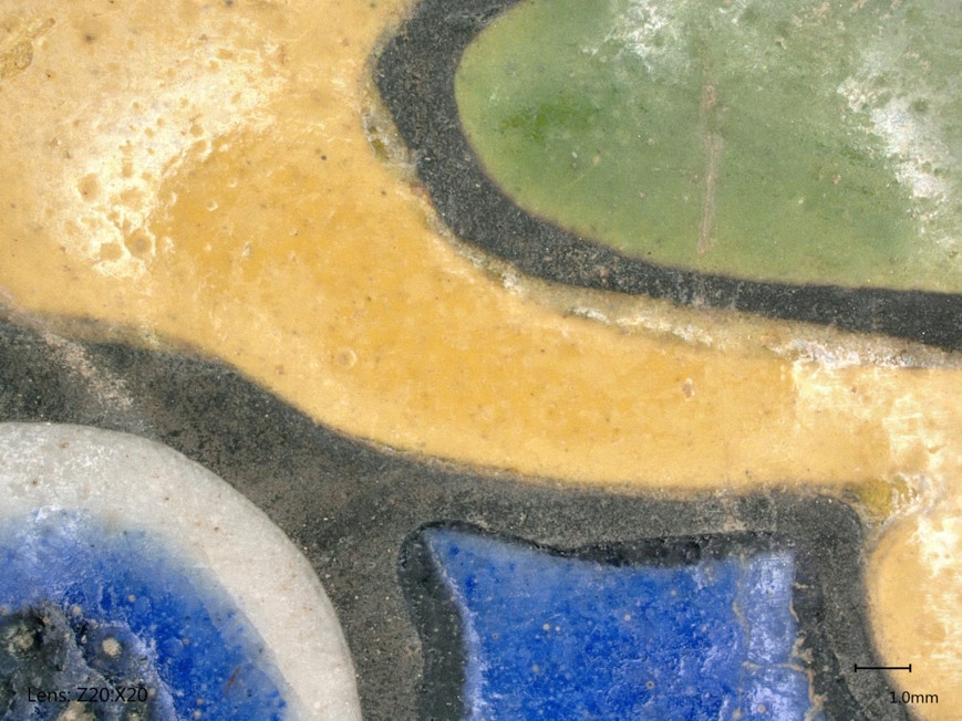 Close-up of a colorful surface showing sections of blue, yellow, white, and green with visible texture.