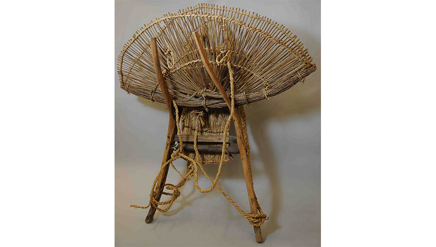 Large woven basket chair with a circular, open weave backrest and a ladder-style support frame.