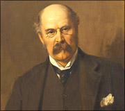 Portrait of an older man with a bald head and mustache wearing a dark suit and tie.