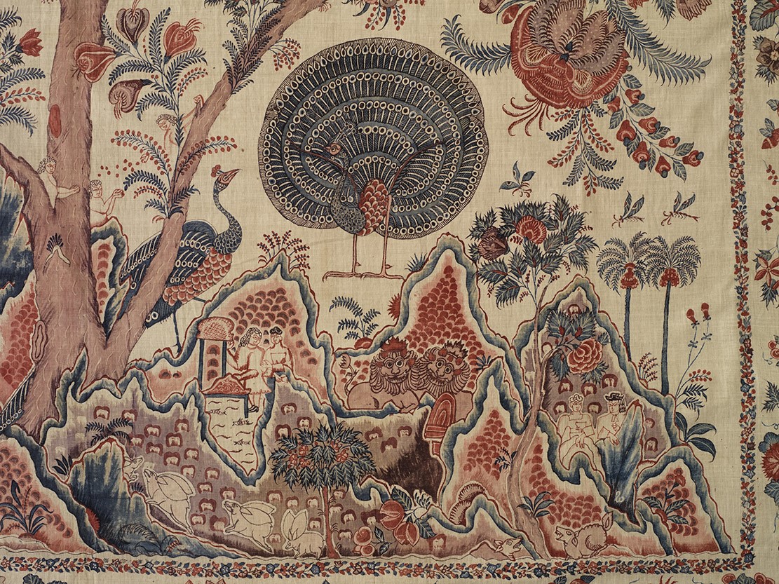 Intricate textile featuring a central peacock with a fan-shaped tail surrounded by floral and architectural motifs.