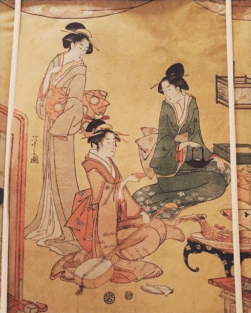 Three women in traditional Japanese clothing, one seated playing a musical instrument, the others standing nearby.