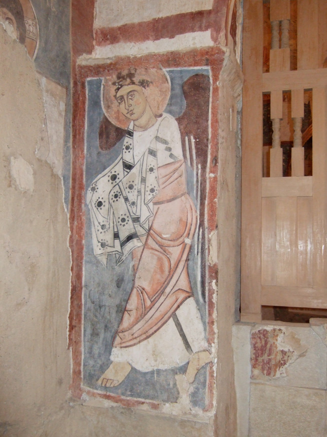 Faded wall painting of a haloed figure wearing a patterned robe and mitre.