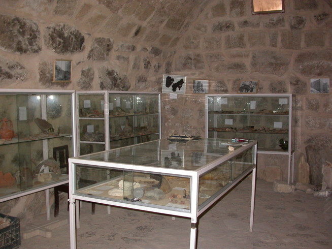 Glass display cases filled with various artifacts inside a stone-walled room.