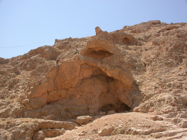 Rock formation with a small cave or hollow in a dry, rocky hillside.