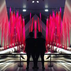 Photo of two people standing in front of a glass art piece