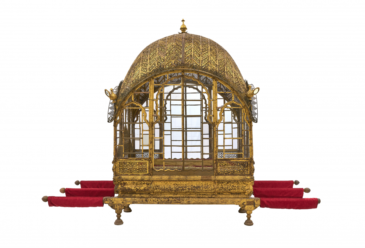 Golden royal palanquin with red carpets on its four extending poles and decorative finials.