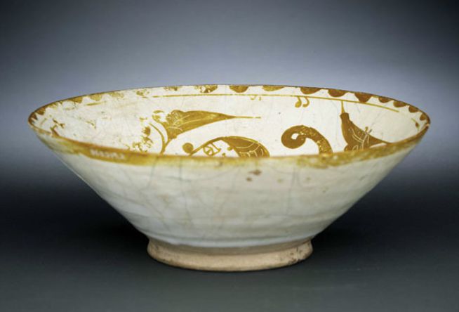 White ceramic bowl with gold floral and vine decoration around the interior rim.
