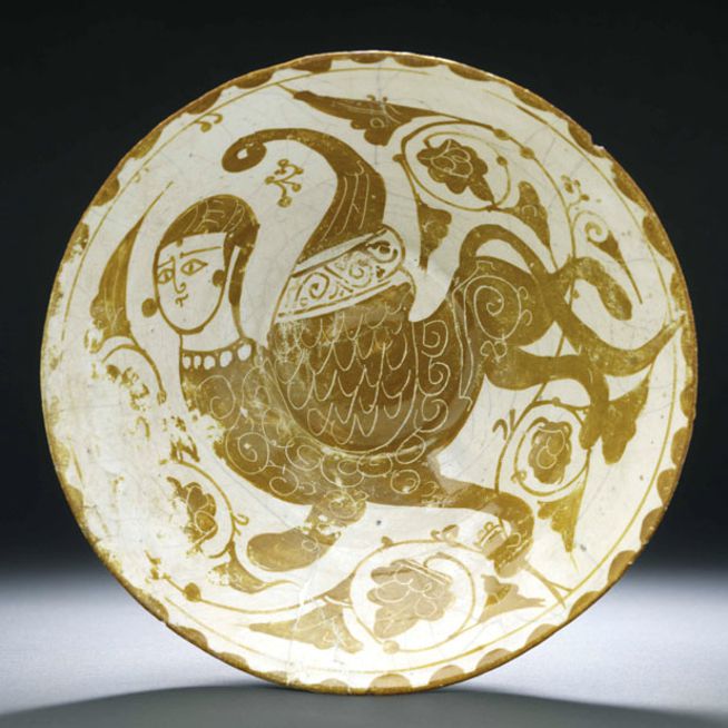 Ceramic plate adorned with a winged, human-headed mythical creature surrounded by swirling vine-like patterns.