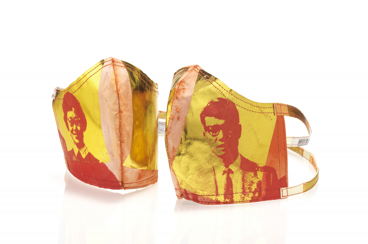 Two protective face masks with yellow backgrounds and red stylized portraits of people printed on the fabric.