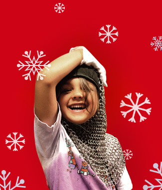 Child smiling and wearing a chainmail coif on a red background with white snowflakes.