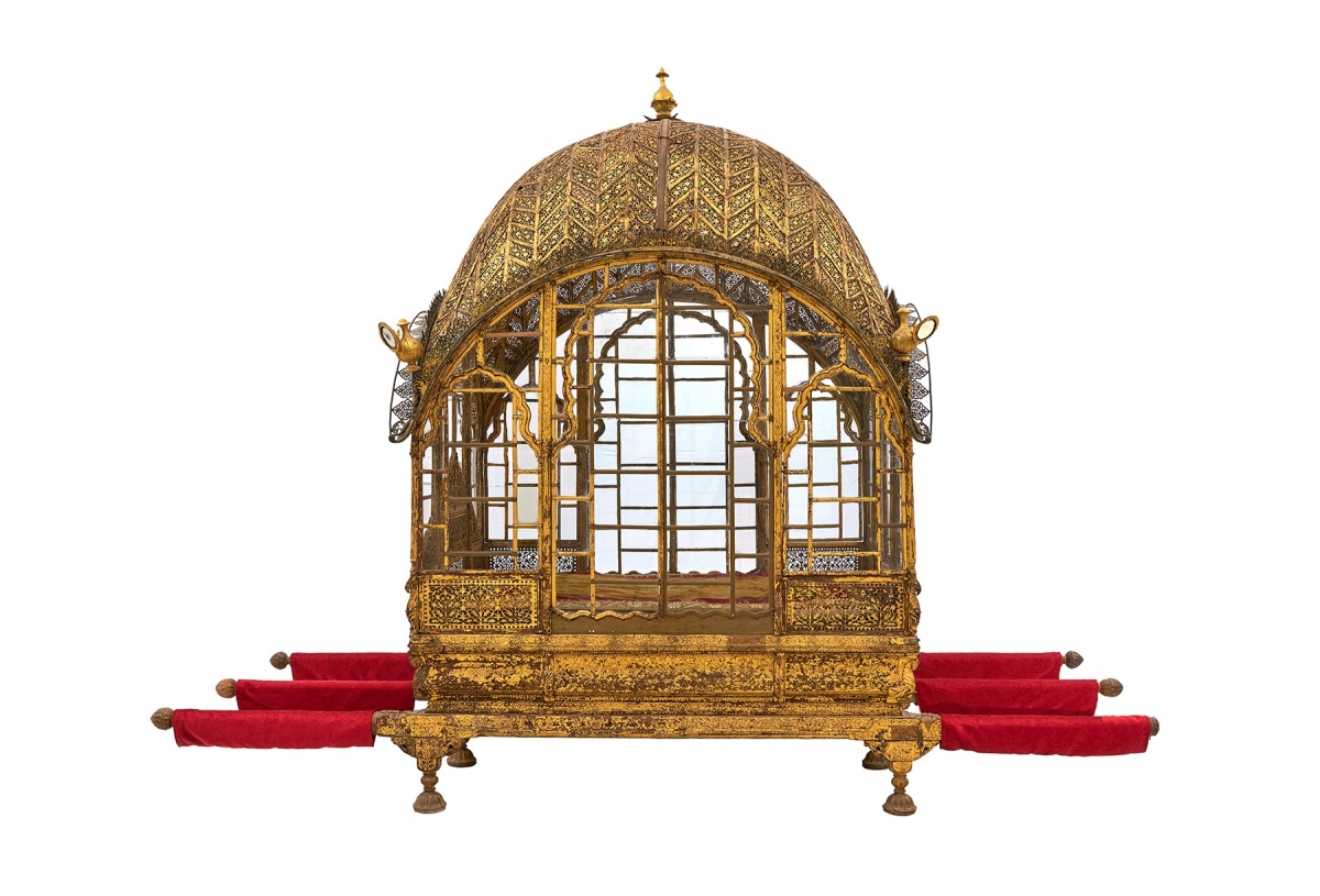 Intricately carved golden palanquin with a domed roof and red fabric-covered poles for carrying.