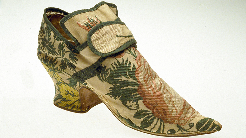 Chaussure en soie brodée du XIXe siècle avec des motifs floraux et de feuilles dans des tons verts, roses et jaunes.
