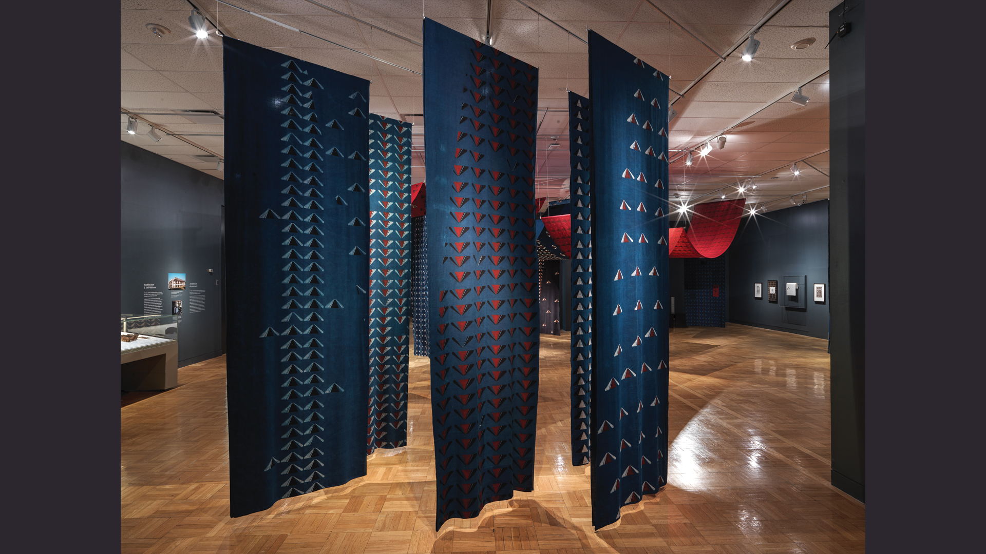 Section de panneaux suspendus en tissu de coton bleu imprimé dans l'exposition Swapnaa Tamhane : Mobile Palace, au ROM.