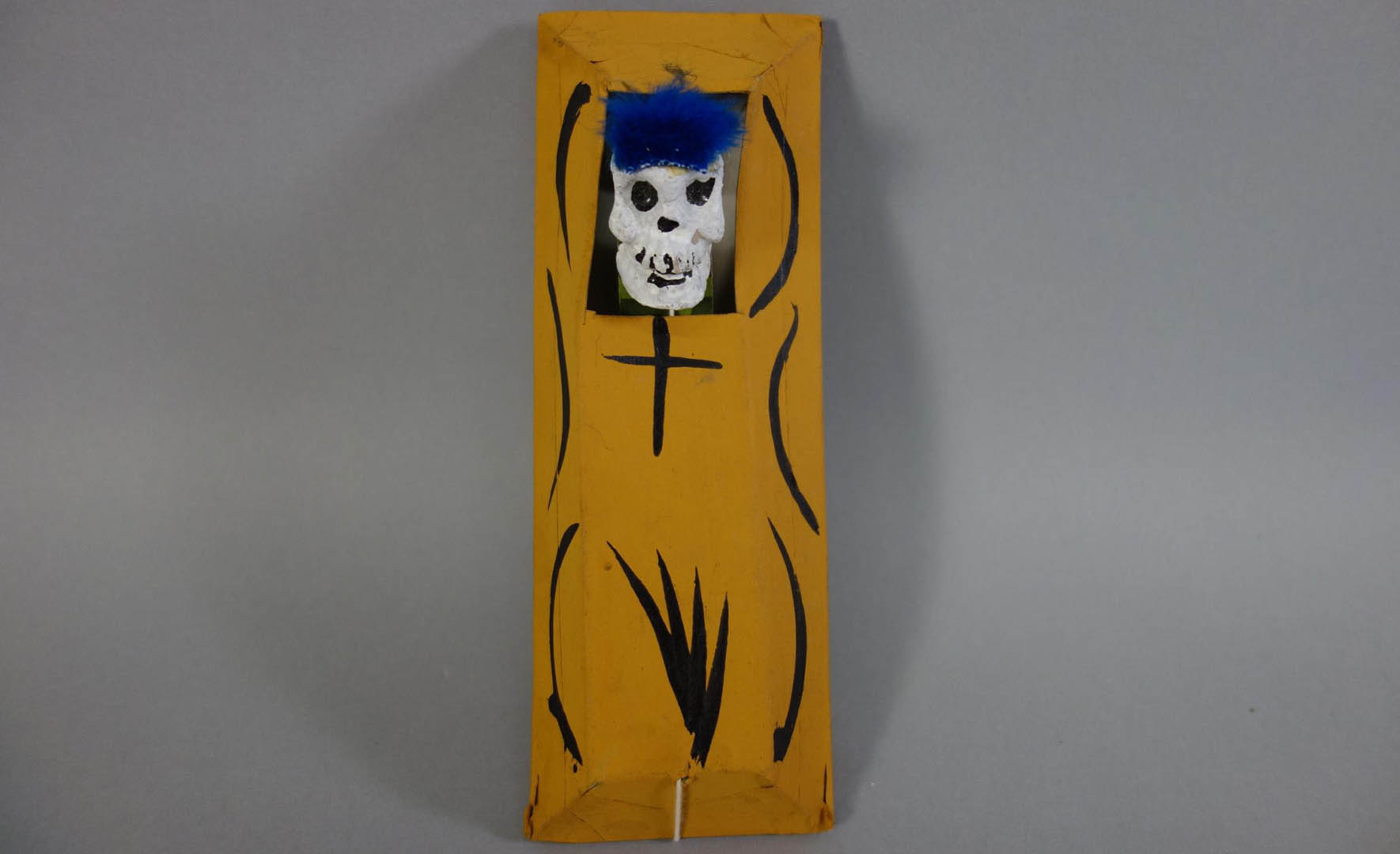 Yellow rectangular object with black curved lines and a small white skull at the top.