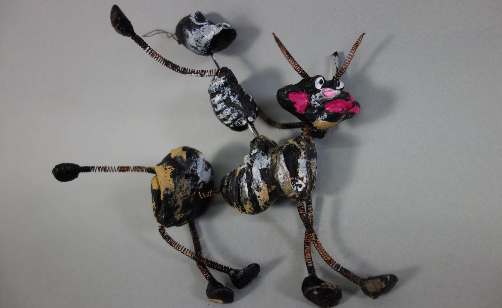 Small animal figure made of painted twigs and sticks on a gray background.