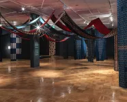 Vue panoramique d'une installation de sculpture souple composée de longueurs de tissu de coton imprimé suspendues en hauteur.