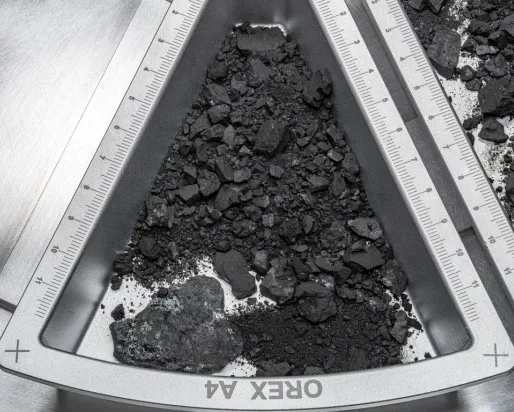 OREX 44 etched on a triangular metal frame holding dark soil and rock fragments.