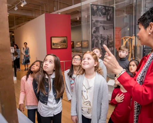 Un groupe d'enfants écoute un guide expliquer une exposition.