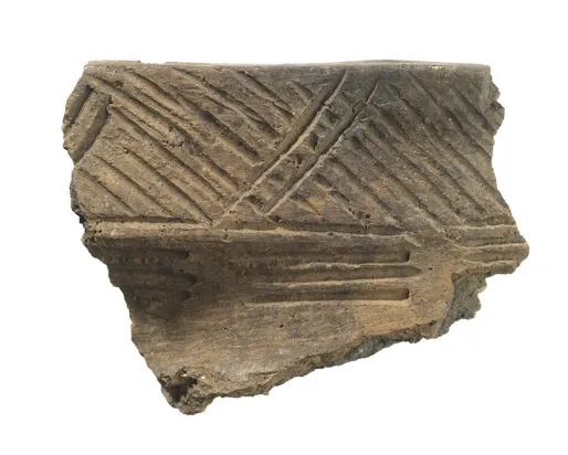 Fragment of pottery with incised diagonal and parallel line decorations.