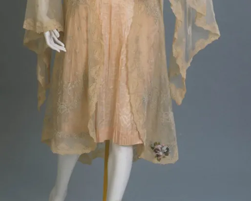 Vintage lace dress with sheer overlay and floral embroidery near the hem.