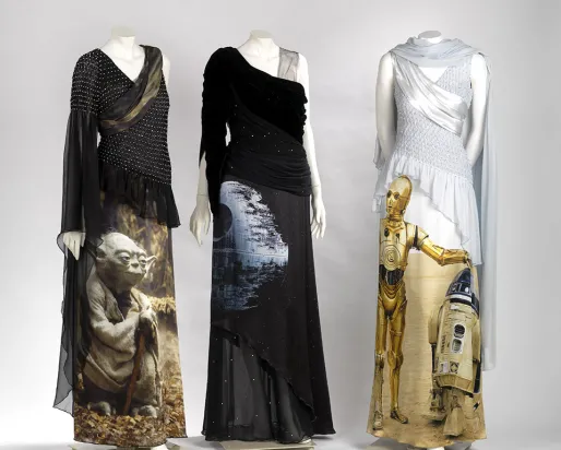 Three mannequins dressed in black and white gowns featuring Star Wars characters C-3PO and Yoda.