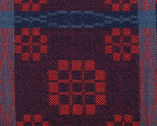 Detail of woven coverlet in red and blue.
