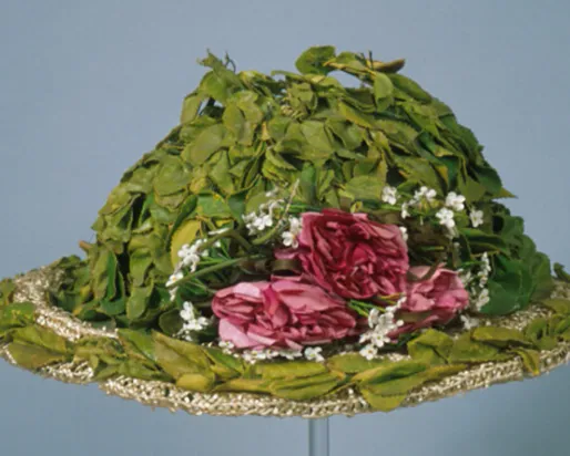 Green hat decorated with pink and white flowers and green leaves, with lace trim.