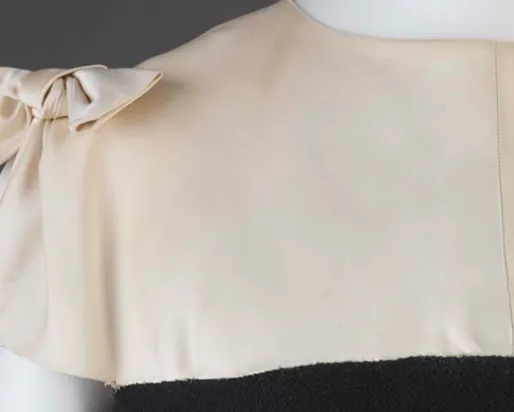 Close-up of an ivory dress bodice with a bow on the left shoulder.