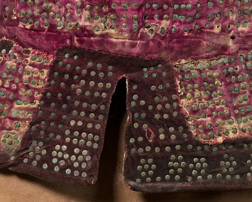 Close-up of fabric decorated with a grid of small metal studs on a red textile background.