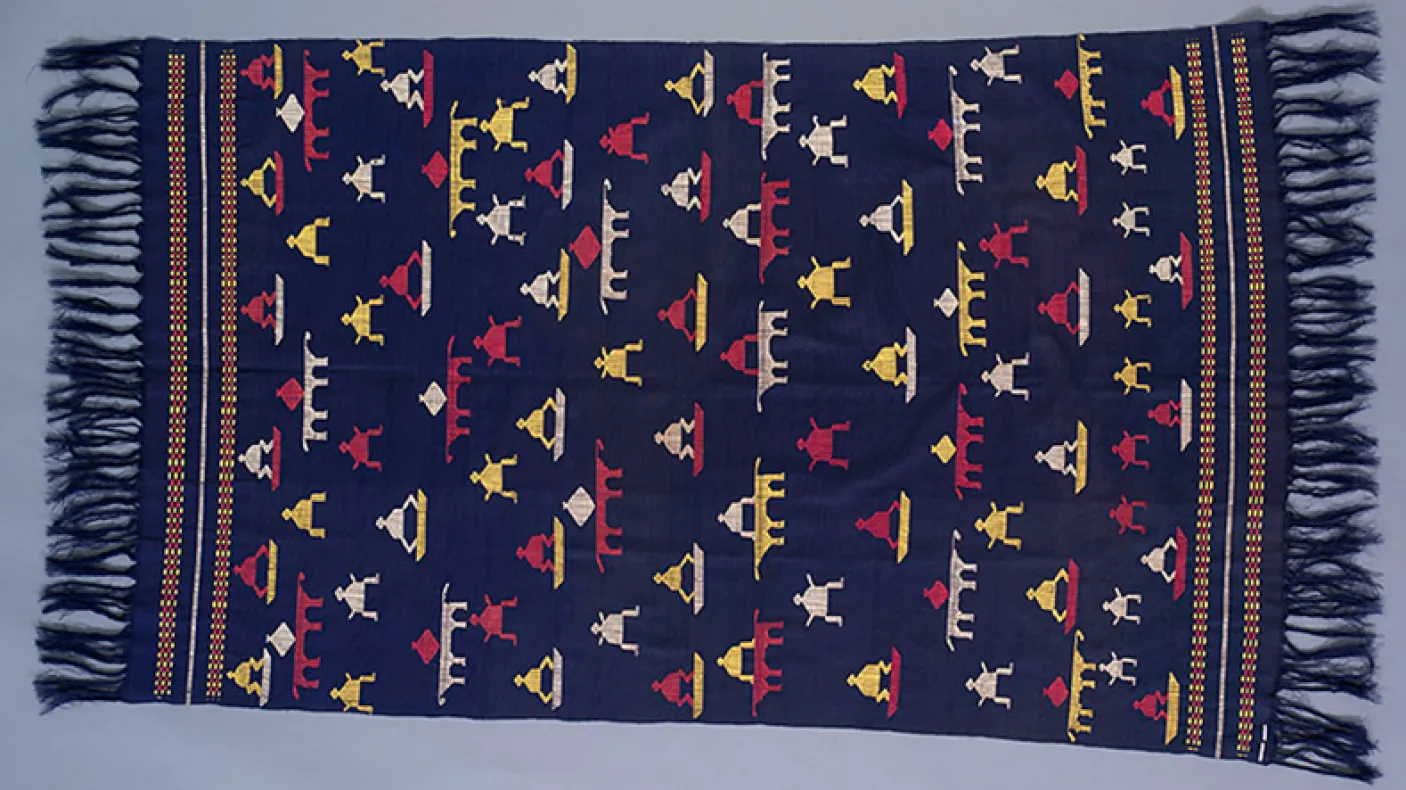 Woven textile with dark blue background and geometric patterns in red, yellow, white, and blue with fringed edges.