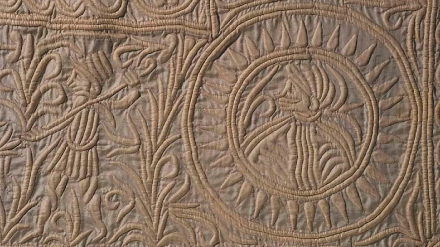 Intricate leaf and flower patterns carved in circular and curved designs on a textured stone surface.