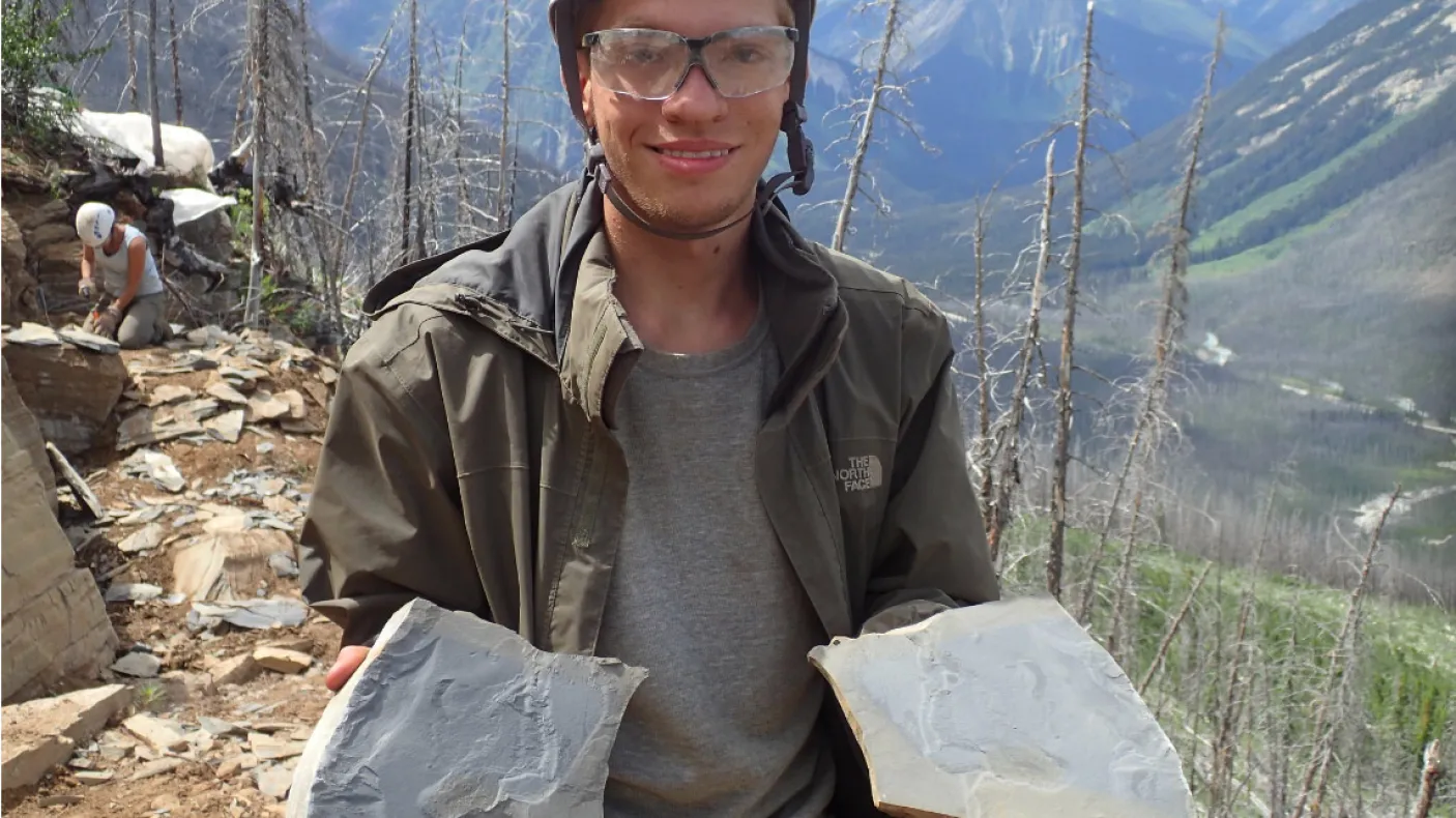 Student holding shale slabs with fossils.
