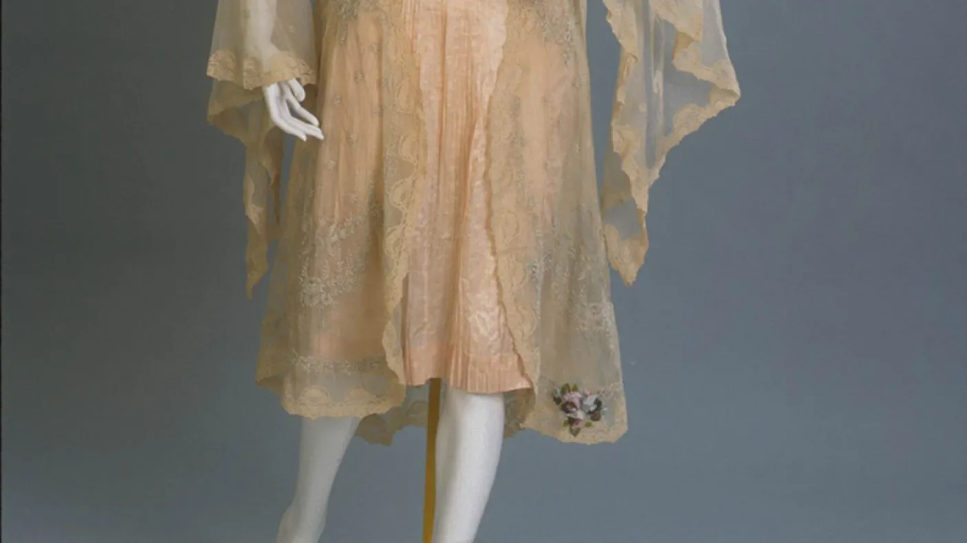 Vintage lace dress with sheer overlay and floral embroidery near the hem.