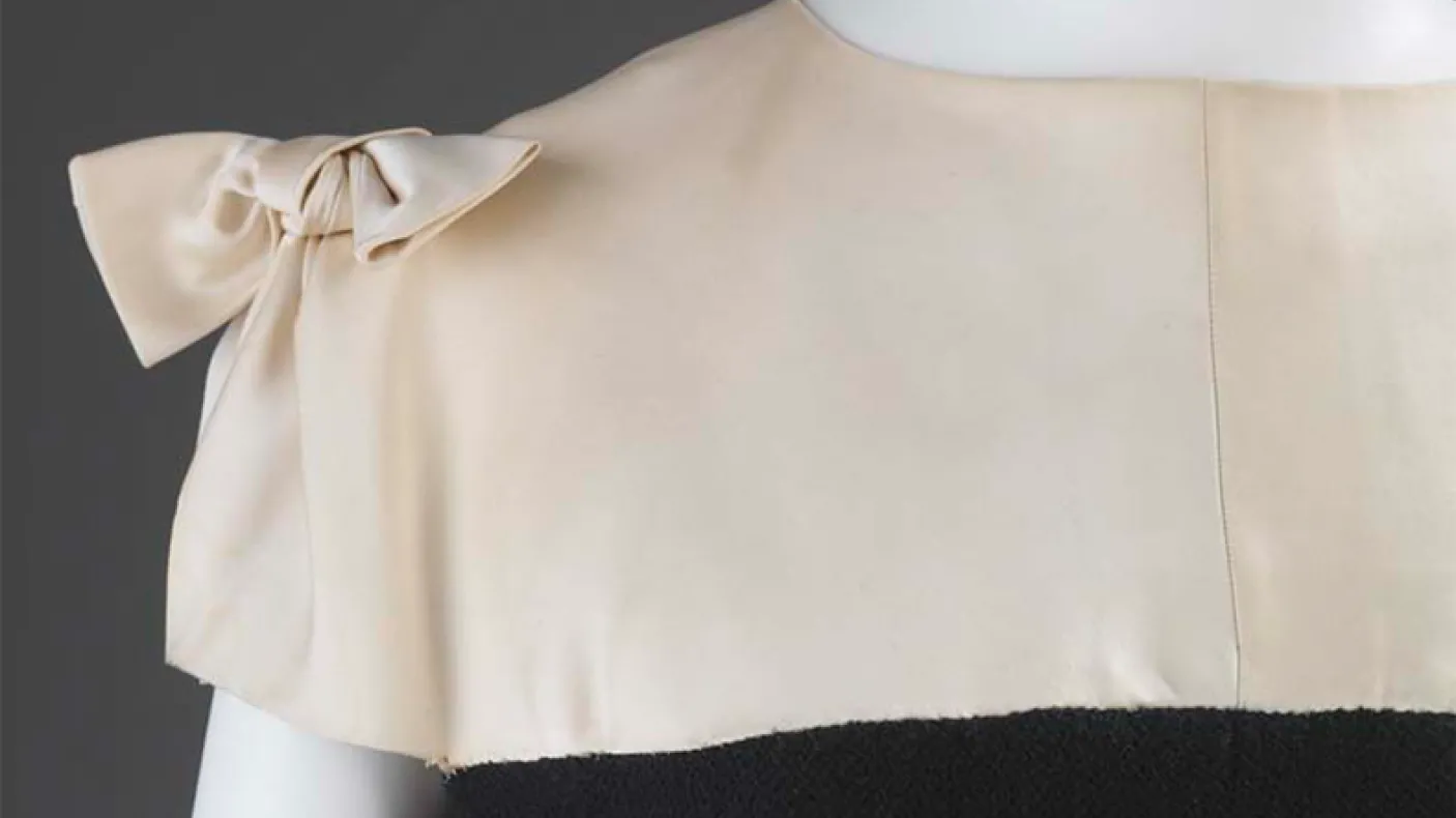 Close-up of an ivory dress bodice with a bow on the left shoulder.