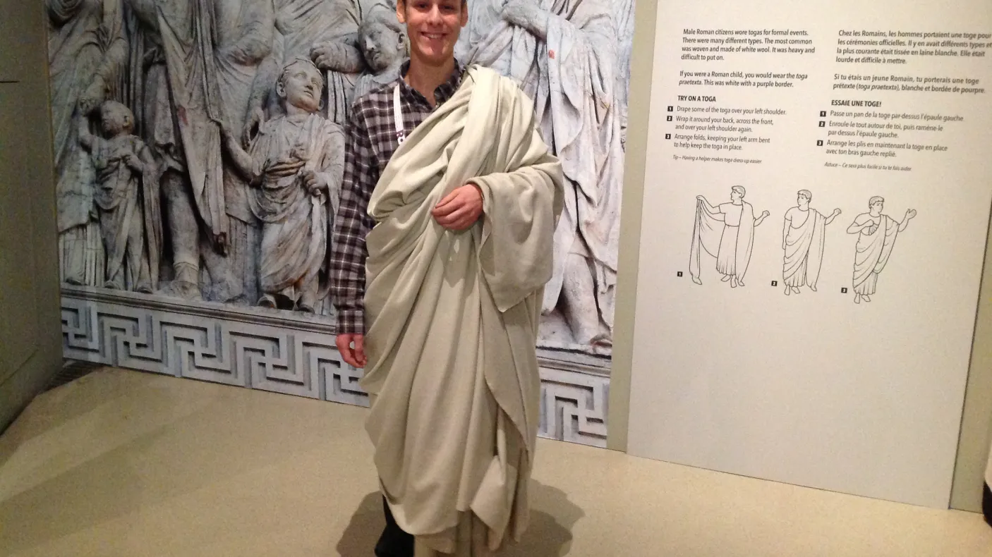 A young man wears a white toga
