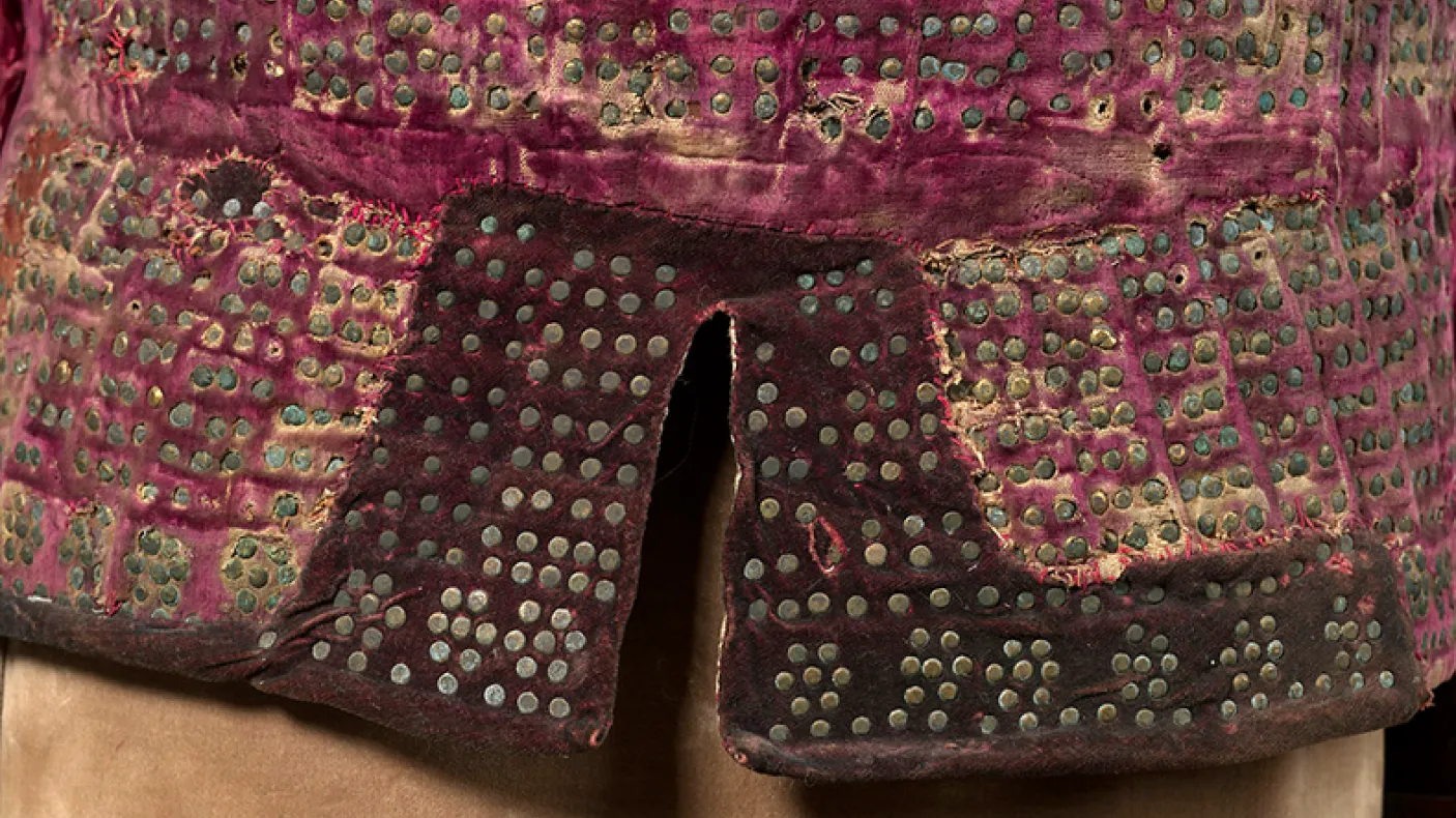 Close-up of fabric decorated with a grid of small metal studs on a red textile background.