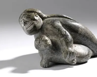 Sculpture of two abstract human figures intertwined, made of dark, textured material.