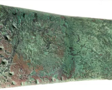 Ancient bronze rectangular axe head with a weathered, textured surface.