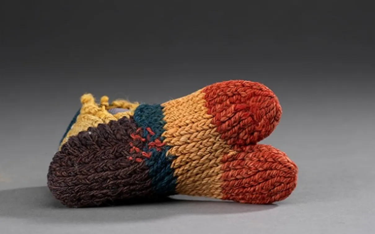 Knitted, multi-colored baby booties in brown, red, and orange.